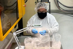 Operador de máquina con capacitación cruzada de Trademark Plastics inspeccionando piezas moldeadas, bajo lupa.