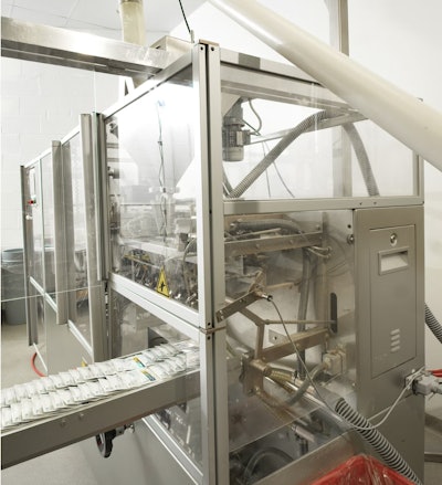 La transportadora de tornillo flexible alimenta la máquina de llenado de bolsas en un espacio reducido. El PLC del sistema acciona un vibrador en la tolva para promover el flujo hacia la transportadora de tornillo flexible y opera la transportadora a velocidad variable y en reversa.