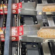 Aguas arriba del empaque secundario, las tartas individuales se cargan en cajas de cartón en este sistema.