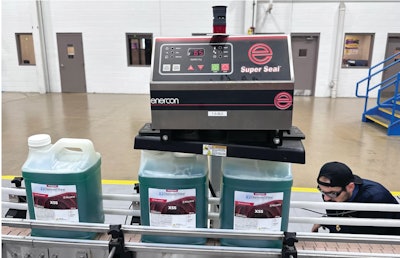 A medida que las botellas tapadas pasan por debajo de este equipo, un sistema de sellado por infrarrojos calienta lo suficiente la tapa de aluminio colocada con precisión que descansa sobre el borde de la botella, debajo de la tapa, de modo que la lámina y la botella se adhieran entre sí.