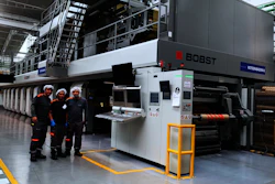 Operadores de prensa de Minipak frente a la prensa de rotograbado de BOBST en la planta de producción del convertidor de empaques flexibles colombiano.
