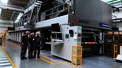 Operadores de prensa de Minipak frente a la prensa de rotograbado de BOBST en la planta de producción del convertidor de empaques flexibles colombiano.