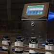 VideoJet industrial inkjet printer with display screen and ink bottles arranged on conveyor line