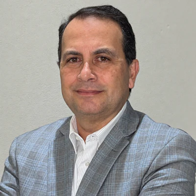 Professional headshot of a man in a gray plaid blazer and white shirt against a neutral background