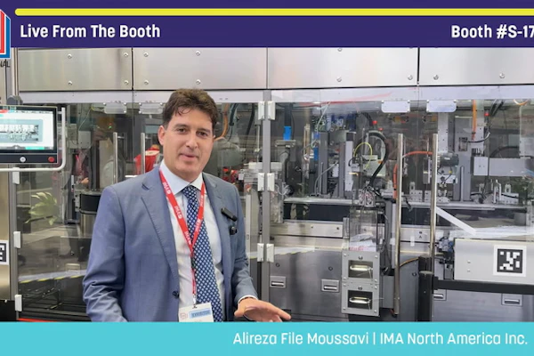 Professional presenter in blue blazer at Pack Expo booth #S-1720 standing before industrial packaging machinery display