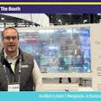 Man presenting at Pack Expo booth #S-3714 with Duravant D-SCADA industrial automation display