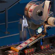 Industrial labeling machine applying labels to products on a blue conveyor belt production line