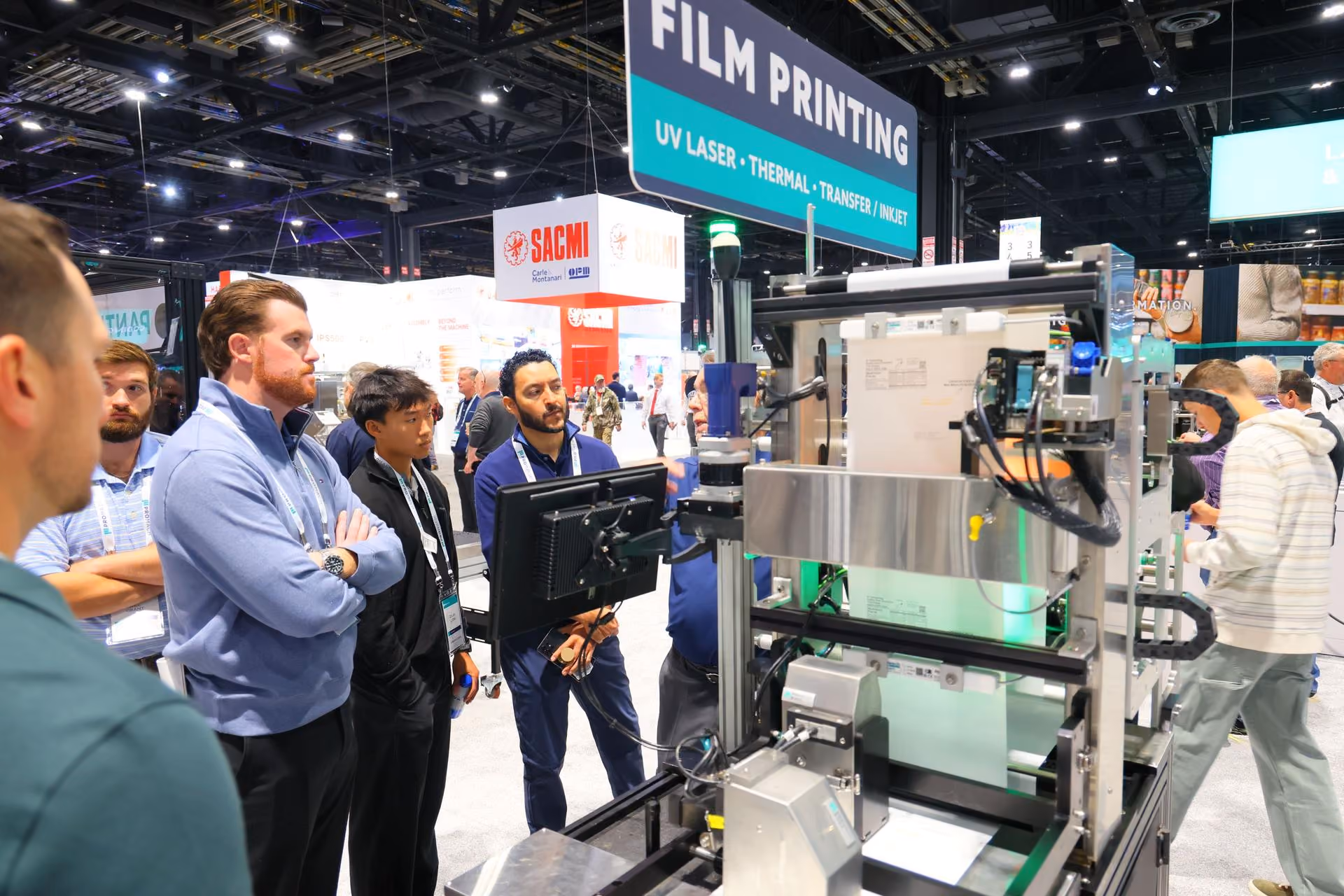 Visitors observe industrial film printing machinery at a trade show booth with UV laser thermal transfer technology signage