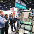 Visitors observe industrial film printing machinery at a trade show booth with UV laser thermal transfer technology signage