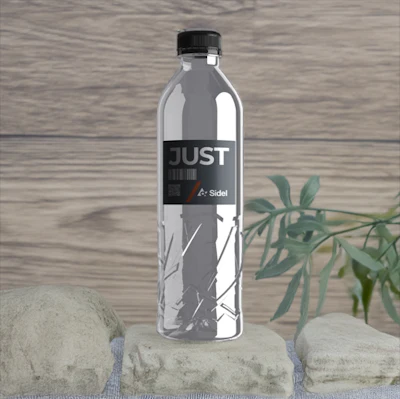 JUST Water bottle with black label on wooden background with stones and green plant